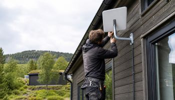 Montør utfører installasjon av Starlink på en hytte i Trøndelag.